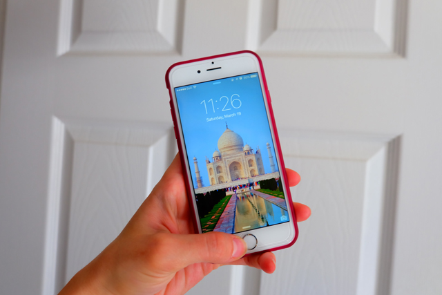 Hand holding an iPhone with the Taj Mahal as the background.