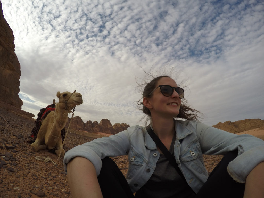Girl sitting in the desert of Jordan with a camel. 