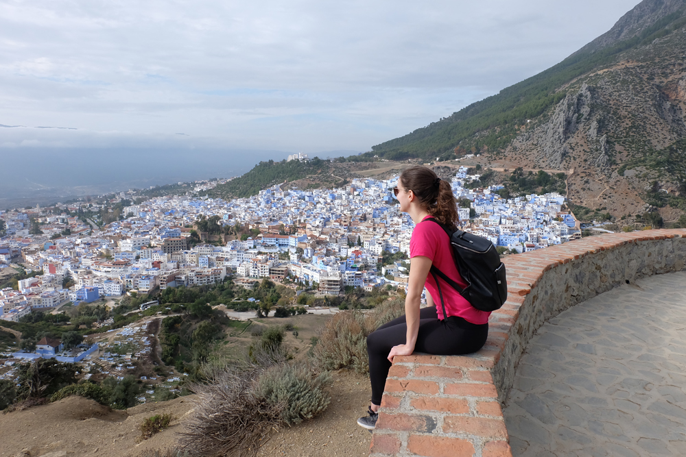 Girl sitting at lookout looking out over the Blue City in Morocco.