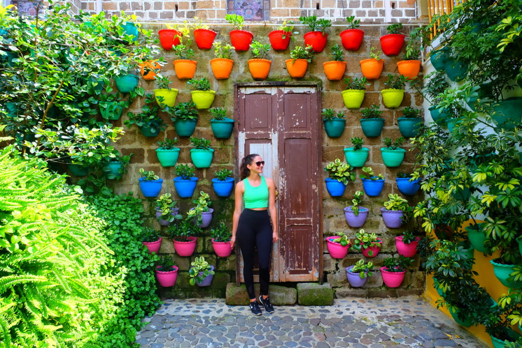 Girl standing in front of a colourful door full of plant pots on a trip to Colombia.