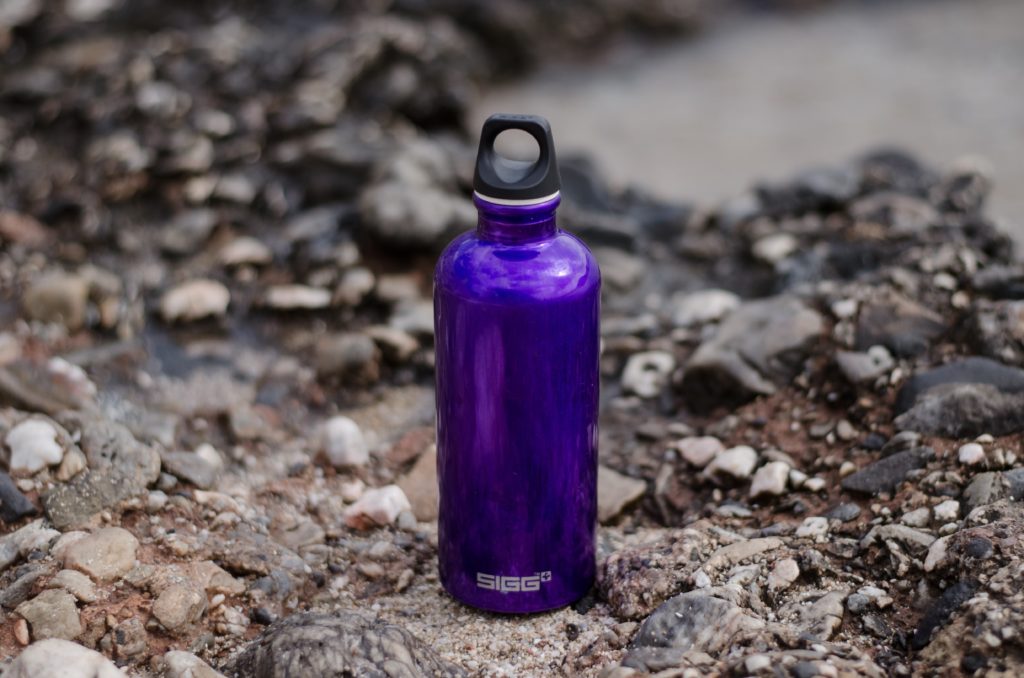 A reusable water bottle on the ground that replaces single-use plastic water bottles.