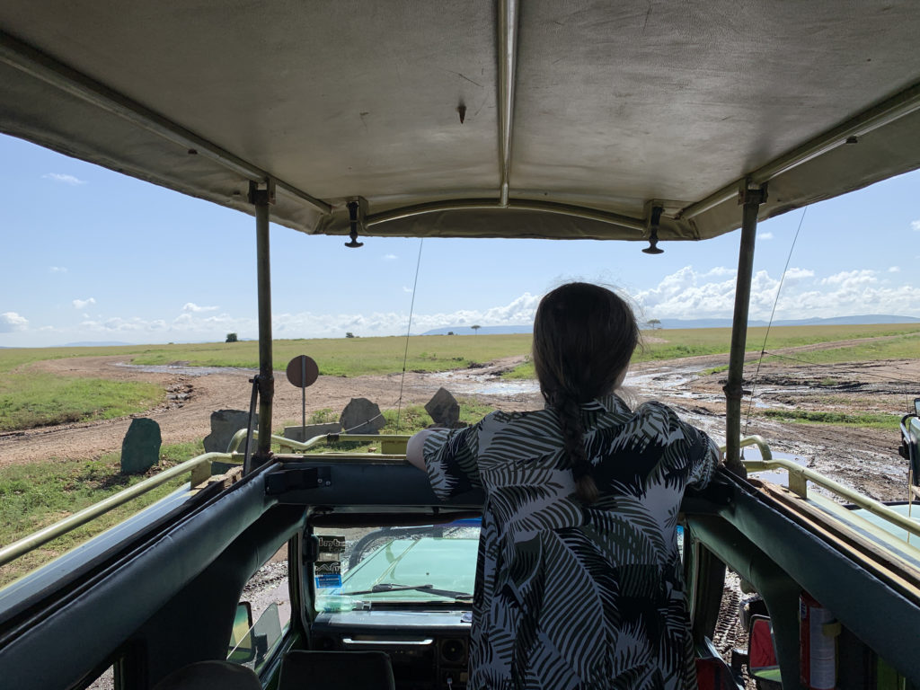Lauren in Kenya looking out of a safari jeep into the wild.