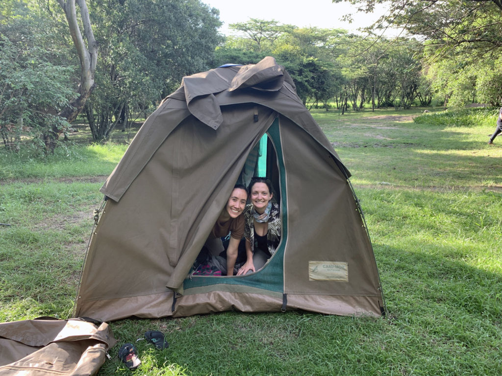 Two girls peaking out of tent on trip through East Africa