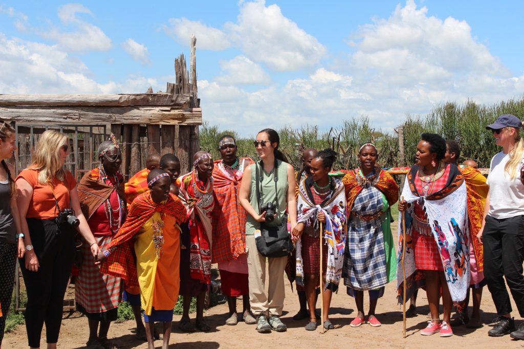 Tourists gathered with women from Maasai Mara in their village.