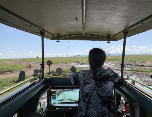 Lauren in Kenya looking out of a safari jeep into the wild.
