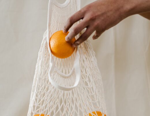 Person putting oranges in a reusable produce bag